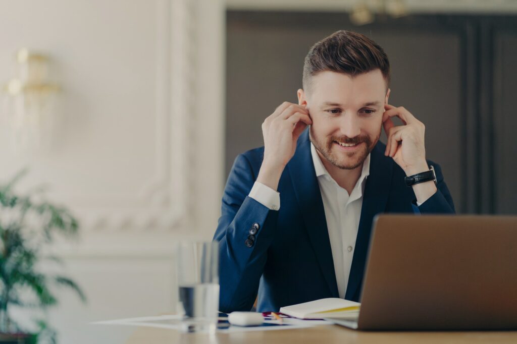 Handsome businessman adjusting earphones during web conference